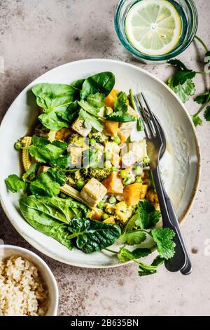 Curry vert végétalien avec tofu, patate douce, maïs et épinards. Concept de nourriture végétalienne saine. Banque D'Images