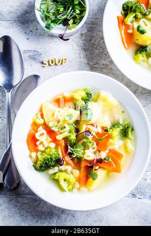 Soupe à l'alphabet pour enfants en bonne santé avec des légumes et des lettres de nouilles dans des assiettes blanches. Concept de nourriture pour bébé. Banque D'Images