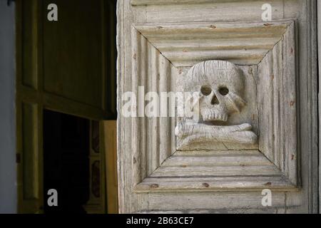 Près de la porte médiévale en bois avec crâne et croisillons sculptés à l'entrée de l'église du purgatoire de Matera, en Italie. Banque D'Images
