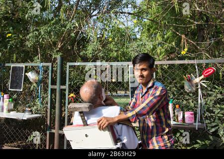 Ahmedabad / Inde / 11 avril 2017: un barbier indien travaillant dans les rues de la ville en une journée ensoleillée Banque D'Images