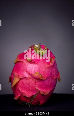 Peau extérieure rose-clé basse du fruit Pitaya ou Dragon à chair blanche sur une surface de texture noire sur fond gris de studio Banque D'Images