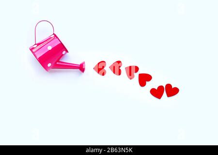 Arrosoir rose avec coeur en bois façonné sur fond blanc, le concept de Saint Valentin. Espace de copie Banque D'Images