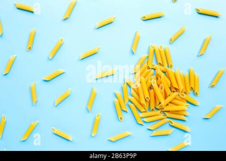 Pâtes de la penne non cuites isolées sur fond bleu. Vue de dessus Banque D'Images