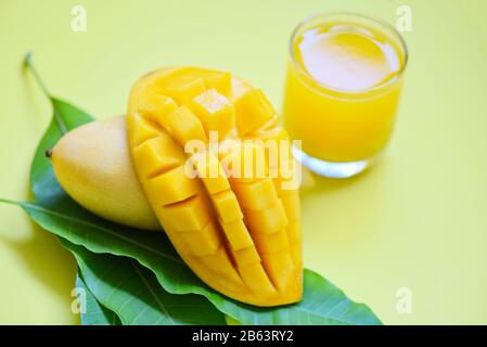 Jus d'été de mangue en verre avec une tranche de mangue mûre douce sur les feuilles vertes du concept de fruits tropicaux d'arbre Banque D'Images
