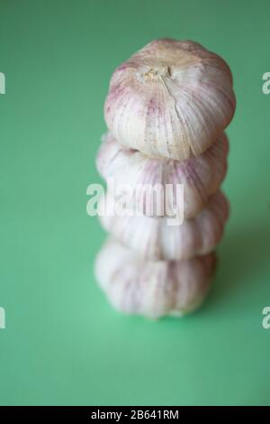 Pile de bulbes d'ail sur fond vert. Gros plan de légumes de saison. Aliments frais biologiques sains. Ingrédient culinaire épicé. Arrière-plan de récolte Banque D'Images