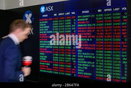 Sydney, Australie. 10 mars 2020. Un journaliste passe devant un conseil d'administration électronique à la Bourse australienne (ASX) à Sydney, en Australie, le 10 mars 2020. Le marché australien des actions a ouvert mardi un peu plus bas malgré les inquiétudes liées à des pertes plus lourdes suite à un faible plomb des marchés étrangers. À 10 h 30 (AEST), l'indice de référence S&P/ASX 200 a diminué de 22,30 points, soit 0,39 pour cent à 5 738,30, tandis que l'indice général De Tous les ordinaires a diminué de 29,10 points, soit 0,50 pour cent à 5 793,30. Crédit: Bai Xuefei/Xinhua/Alay Live News Banque D'Images