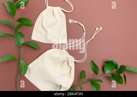 Sacs en toile et feuilles vertes sur fond brun. Concept zéro déchet. Banque D'Images