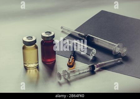 Médicaments, seringues, ampoules sur fond gris. Deux ampoules, deux seringues et deux flacons avec médicaments. Prise de vue au niveau des yeux. Gros plan. Sélectif f Banque D'Images