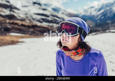 Bonne fille vêtue de lunettes de masque de mode pour le ski ou le snowboard. Paysage de montagne. Aventure extrême. Station de ski d'hiver Banque D'Images