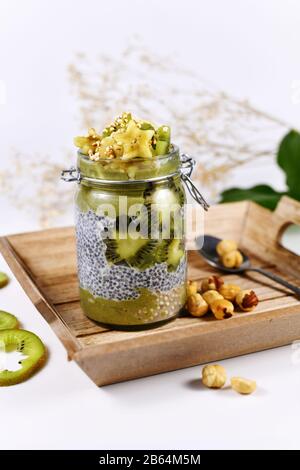 Smoothie aux fruits verts en verre avec pudding aux graines de chia recouvert de tranches de banane en forme d'étoile et de kiwi Banque D'Images