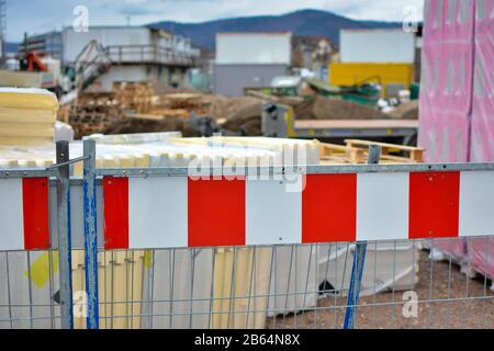 Barrière de chantier à rayures rouges et blanches avec travaux de construction flous en arrière-plan Banque D'Images