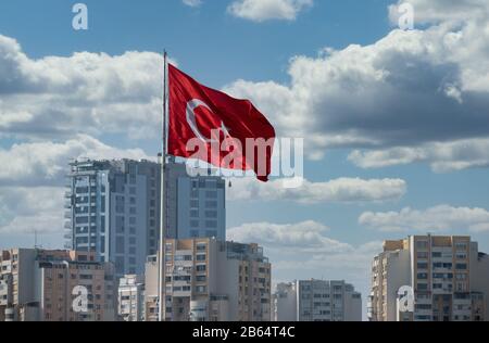 Drapeau turc agitant devant la grue de construction et les nuages. Contexte. Banque D'Images