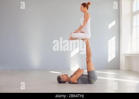 Un couple de yoga pratique le yoga acro sur le sol dans un cours de studio. Banque D'Images