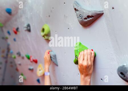 Climber mains tenant boulder en salle d'escalade artificielle, closeup shot Banque D'Images