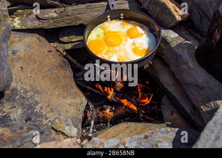 œufs frits dans une poêle en fonte sur le feu de camping Banque D'Images