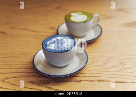 Matcha bleu et vert dans des mugs blancs en céramique sur une table en bois avec copyspace. Banque D'Images