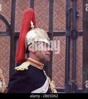 Années 1960, historique, gros plan du visage et casque en acier poli et or d'un gardien de cheval britannique, Windsor Castle, Windsor & Eton, Berkshire, Angleterre, UK, membre du Royal Regiment of Horse Guards, connu sous le nom de Blues, un régiment de cavalerie de l'armée britannique, faisant partie de la Household Cavalry. Les Blues fusionnent avec un autre régiment, les Royal Dragoons en 1969. Banque D'Images