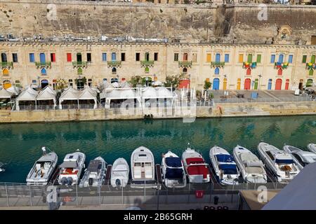 Des bateaux à moteur et des bateaux amarrés dans une petite marina au bord de l'eau de la Valette, devant Les Cafés et Les Restaurants du Quayside. Banque D'Images