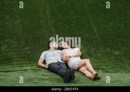 couple amoureux reposant sur l'herbe artificielle verte Banque D'Images