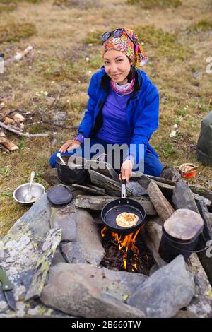 Cuisine dans le camp à l'extérieur. Marmite bouillante sur le feu de camp avec crêpes Banque D'Images