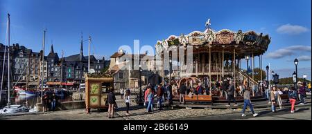 Honfleur, Calvados, Normandie, France. Honfleur est situé sur l'estuaire de la Seine, près du célèbre pont normand Honfleur est célèbre pour son port pittoresque, y compris des bâtiments colorés et des maisons avec des façades couvertes d'ardoise. Le port d'Honfleur a été peint à plusieurs reprises par des artistes qui ont donné naissance aux mouvements impressionnistes : Claude Monet, Gustave Courbet et Eugène Boudin. Carrousel, chevaux en bois Banque D'Images