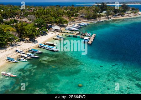 Vue aérienne des bateaux amarrés au large d'un beau récif tropical de corail et de la plage sur une petite île (Gili Air, Indonésie) Banque D'Images