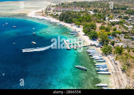 Vue aérienne des bateaux amarrés au large d'un beau récif tropical de corail et de la plage sur une petite île (Gili Air, Indonésie) Banque D'Images