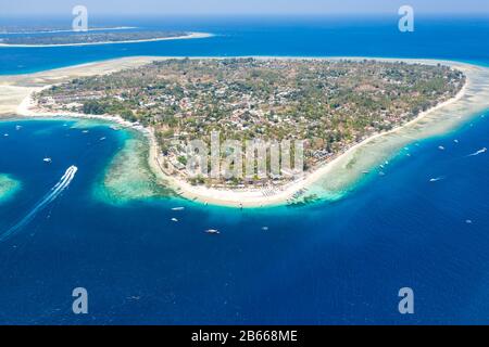 Vue aérienne d'une magnifique île tropicale entourée d'un récif de corail frangeant et d'un océan bleu profond Banque D'Images