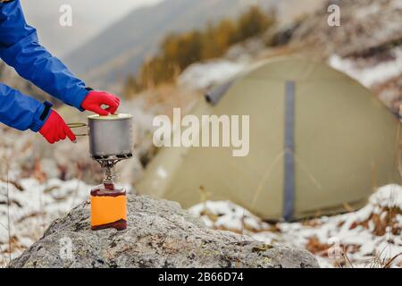 poêle à jet de camping à cartouche de gaz avec pot moderne en titane sur un fond de tente pendant la randonnée Banque D'Images