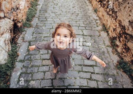 Une jolie fille de bébé tient les bras ouverts et marche sur un sentier sur une allée médiévale Banque D'Images