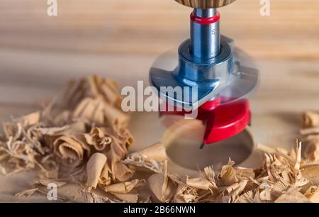 Foret Forstner en acier avec plaque de verrouillage. Alésage du trou cylindrique dans la planche en bois. La vie artistique encore. Magnifique flou de mouvement de l'outil de perçage. Banque D'Images