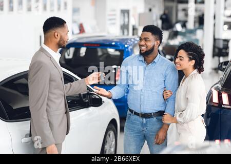 Couple Afro Prenant La Clé Du Responsable De La Location De Voitures Banque D'Images