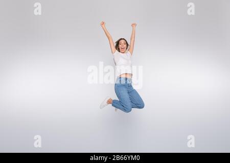 Pleine taille du corps photo de saut heureux magnifique jolie fille attrayante ayant remporté quelques concours tout en étant isolée avec fond blanc Banque D'Images