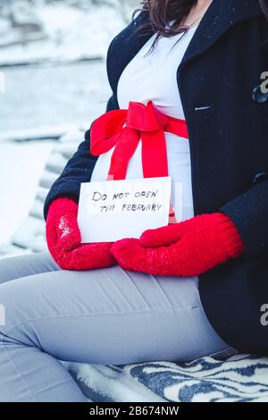 Cesis De La Ville, Lettonie. Une femme enceinte est assise sur un banc en hiver avec un morceau de papier dans sa main. 17.01.2016 Banque D'Images