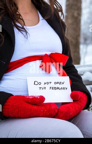 Cesis De La Ville, Lettonie. Une femme enceinte est assise sur un banc en hiver avec un morceau de papier dans sa main. 17.01.2016 Banque D'Images