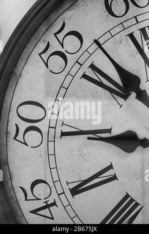 Gros plan noir et blanc d'un cadran d'horloge vintage avec chiffres romains, temps abstrait et concept de délai. Banque D'Images