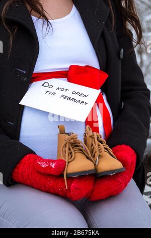 Cesis De La Ville, Lettonie. Une femme enceinte est assise sur un banc en hiver avec un morceau de papier dans sa main. 17.01.2016 Banque D'Images