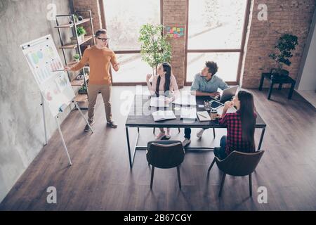 Au-dessus de la vue de grand angle des gars sérieux employés professionnels financiers assistant à la table d'analyse des données de rendez-vous à l'intérieur du loft industriel Banque D'Images