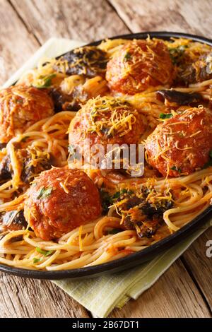 Pâtes spaghetti avec boulettes de viande, champignons et cheddar gros plan dans une assiette sur la table. Vertical Banque D'Images
