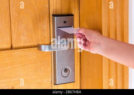 Mettre la main féminine et la tenue de l'interrupteur à clé magnétique pour ouvrir la porte de la salle de l'hôtel. Banque D'Images