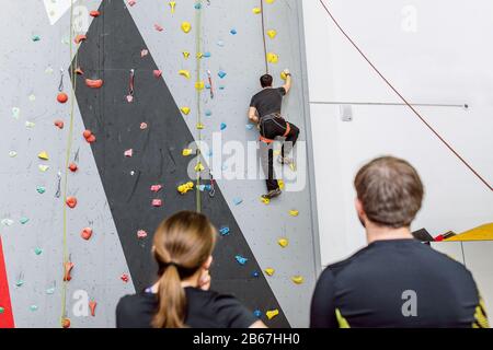 Placez vos amis sur le mur d'escalade artificiel à l'intérieur en discutant des tactiques de bourage Banque D'Images