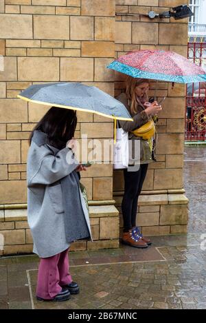 Jeunes femmes avec parasols par jour de pluie au Musée national d'histoire de Londres, Royaume-Uni Banque D'Images