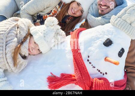 Bonne famille avec un bonhomme de neige de bâtiment pour enfants en hiver Banque D'Images