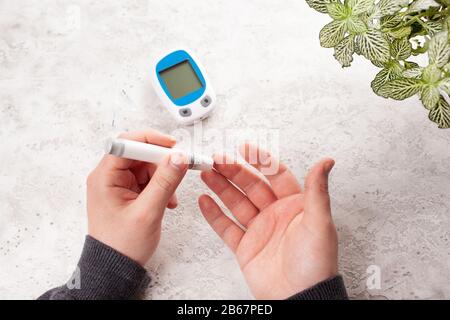 mains de l'homme utilisant lancet sur le doigt pour vérifier le taux de sucre ou de cétones dans le sang par le glucomètre. médecine diabète keto régime de soins de santé à la maison Banque D'Images