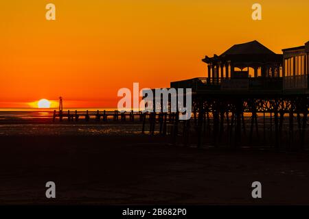 Un ciel doré alors que le soleil se couche derrière la silhouette de l'embarcadère victorien à St Annes on Sea dans Lancashire angleterre Banque D'Images