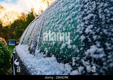 Voiture noire recouverte d'une couche de neige gelée dans la lumière du matin un matin très froid pendant l'hiver au Royaume-Uni. Banque D'Images