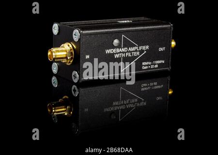 Amplificateur de signal large bande RF et micro-ondes isolé sur la surface réfléchissante noire Banque D'Images