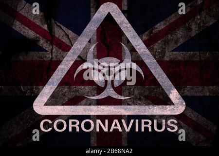 Symbole d'avertissement de risque biologique triangulaire COVID-19 sur un drapeau britannique à grunge foncé (mixte). Banque D'Images