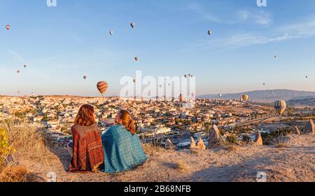 Couple d'amis voyageurs profitant de la vue sur la vallée avec de merveilleux ballons vol au-dessus de la vallée de la Cappadoce en Turquie Banque D'Images