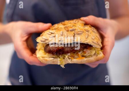 Gros plan sur une personne qui tient des saucisses fraîches bap, un pain semé dans une boulangerie artisanale. Banque D'Images